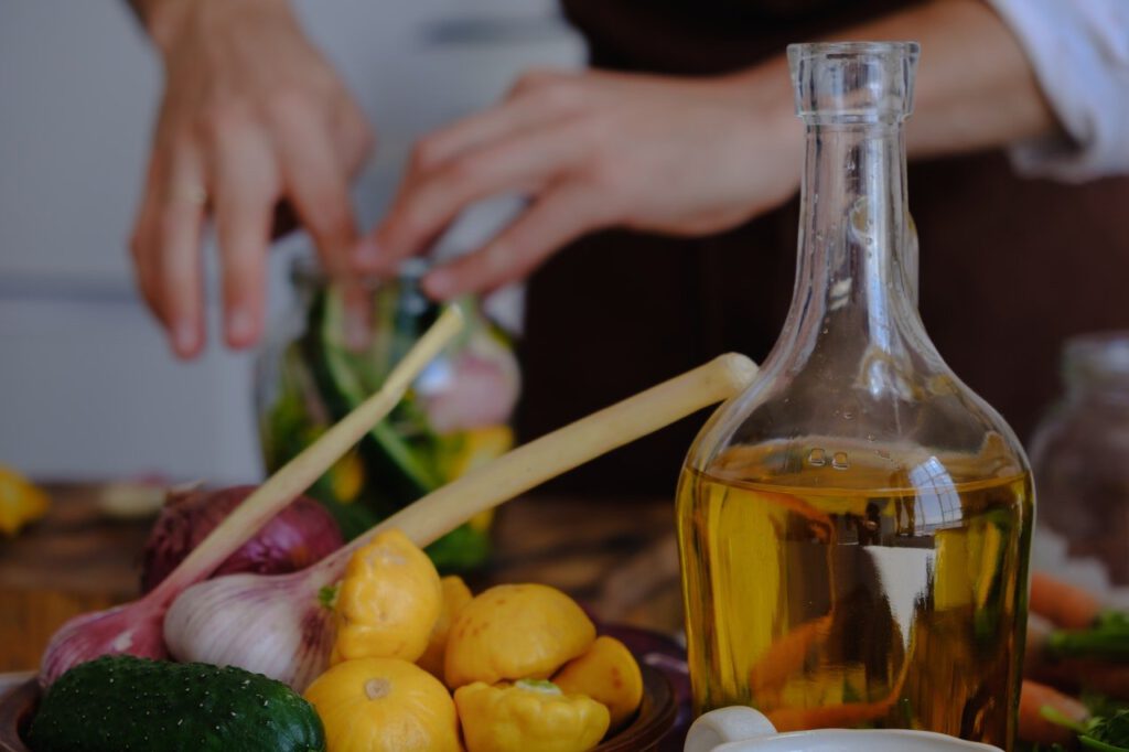 Clear glass bottle filled with cooking oil next to onion and squash