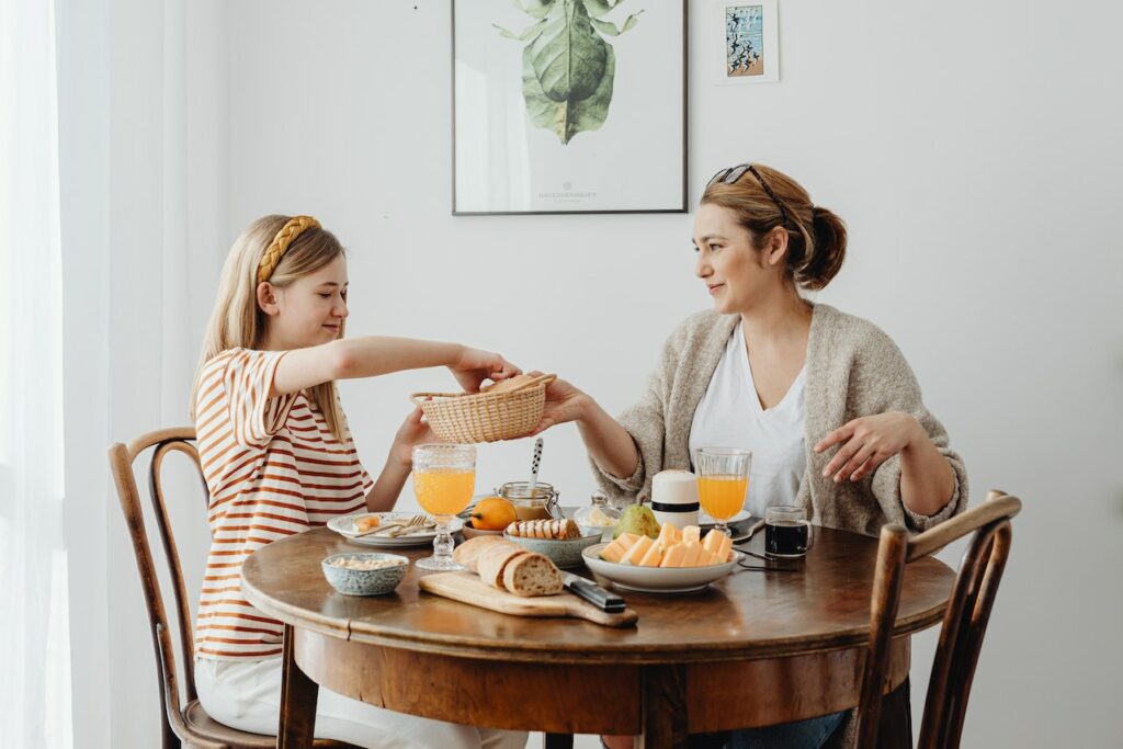 A girl grabbing bread from a basket her mom is holding