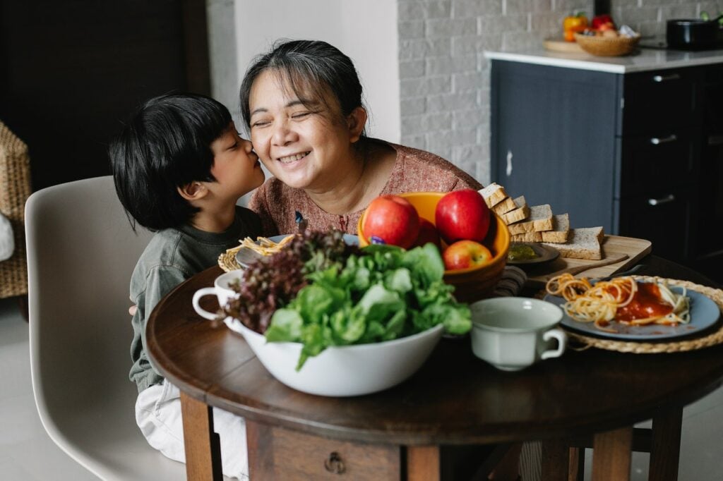 Young child kissing his grandma's cheek sitting at the dinner table