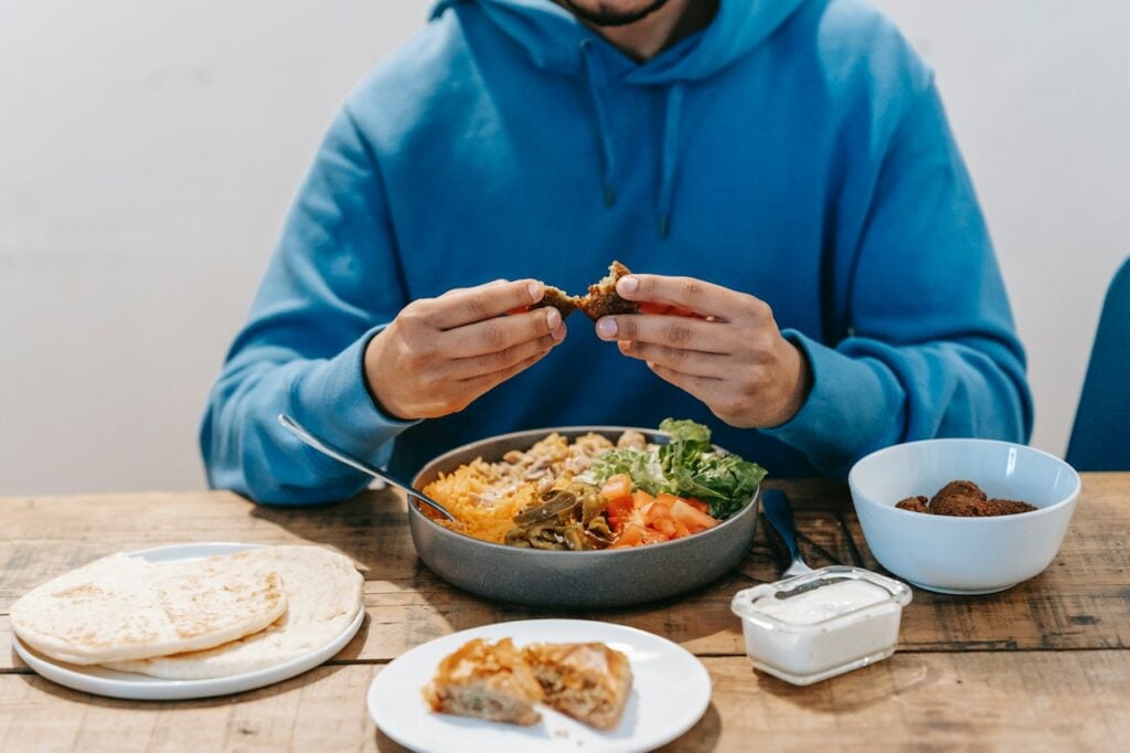 Man eating delicious meat at table with national dish